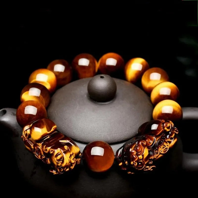 Tiger Eye Beads Feng Shui Bracelet with Pixiu charms placed on a teapot, showcasing its glossy finish and symbolic design.