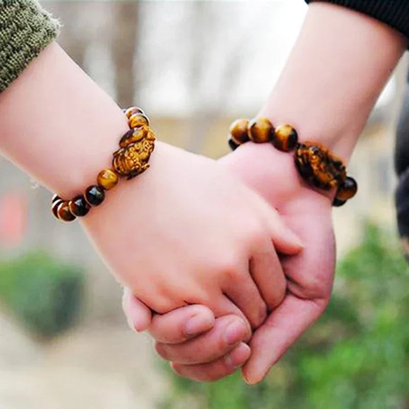 Couple wearing matching Tiger Eye Beads Feng Shui Bracelets with Pixiu charms, promoting good luck and prosperity in relationships.
