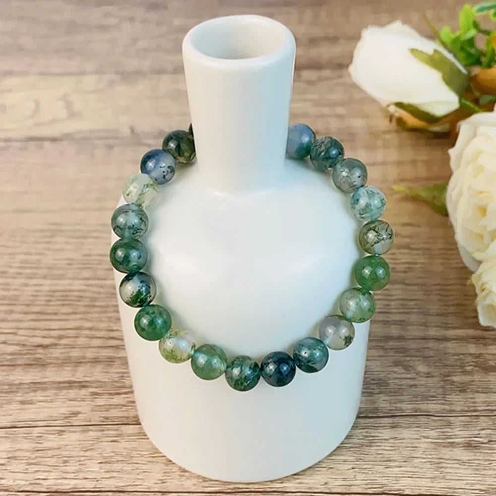 8MM Moss Agate Crystal Bracelet wrapped around a white vase, showcasing natural healing stones for fashion and energy balance.