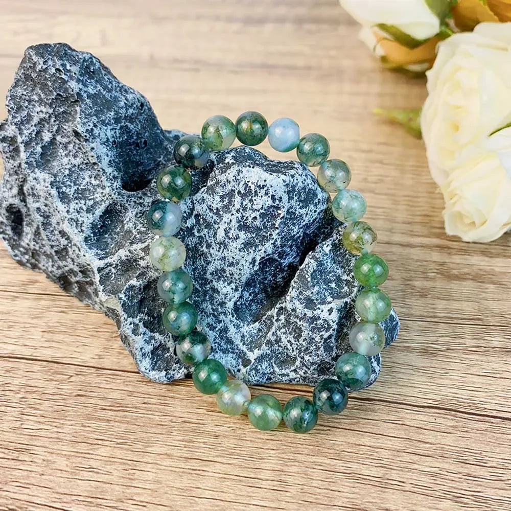 Single 8MM Moss Agate Bracelet displayed on a rock, highlighting natural crystal beads for healing and spiritual wellness.