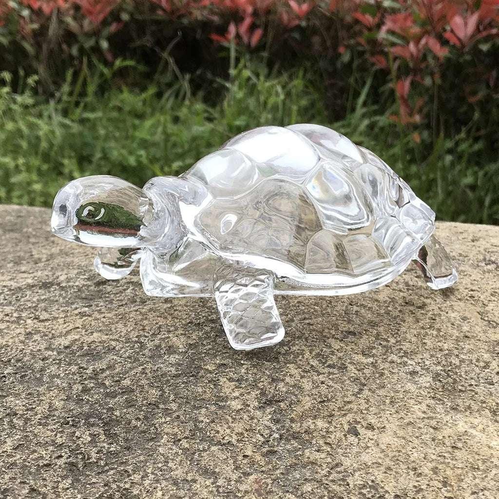 Transparent tortoise figurine placed on stone surface, feng shui crystal turtle for home and garden decoration.