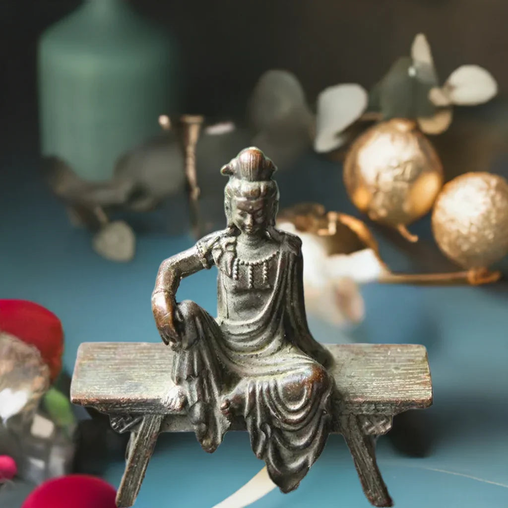 Antique-style Guanyin Bodhisattva bronze statue on bench, featured in a Feng Shui-inspired decorative setting.