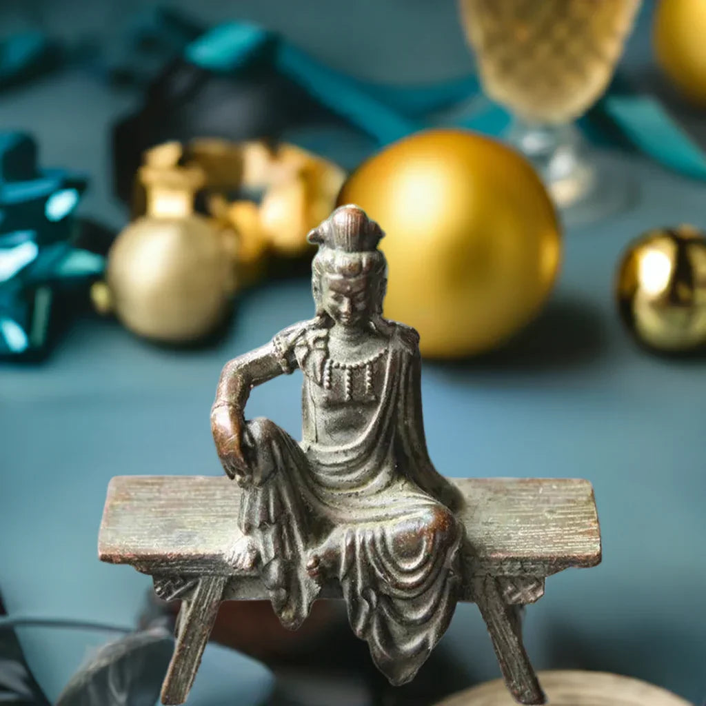 Bronze Guanyin Bodhisattva statue on bench with festive background, perfect for Feng Shui and antique home decor accents.