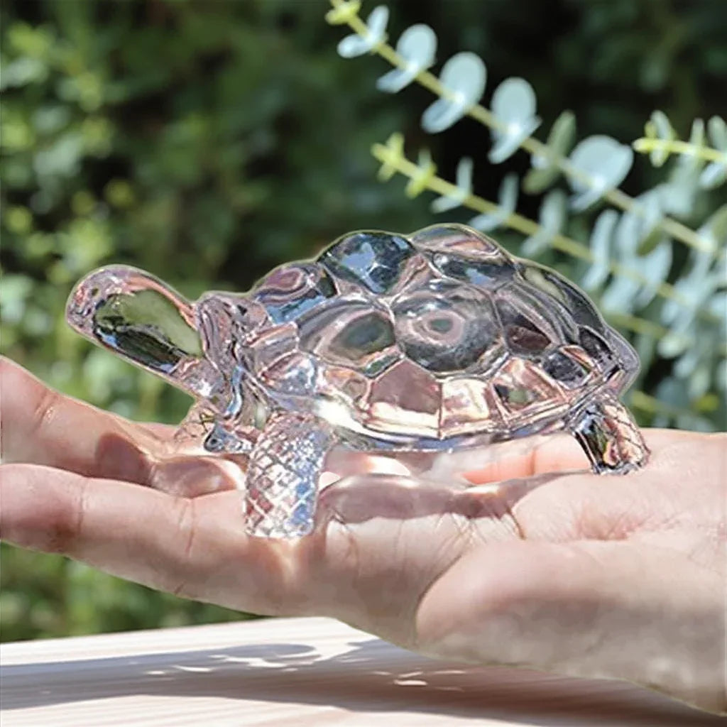 Crystal turtle figurine shown outdoors in hand, symbolizing feng shui luck and harmony for home or office spaces.