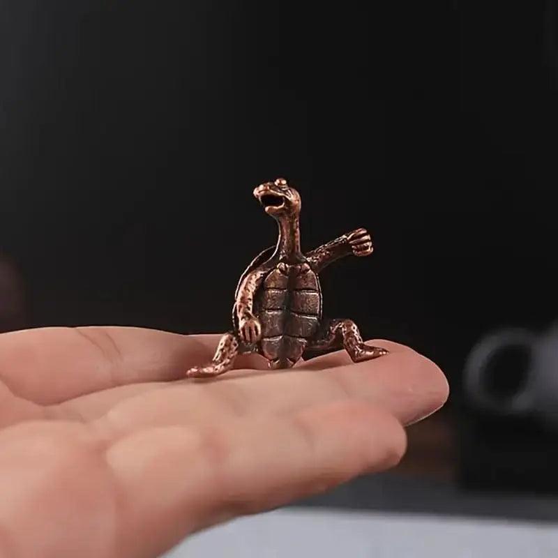 Miniature bronze turtle figurine incense holder with raised arm, suitable for Feng Shui decor and spiritual ambiance.