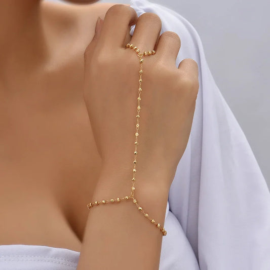 Gold-plated faceted beads hand chain bracelet with finger ring, worn on hand, showcasing minimalist goddess charm jewelry style.